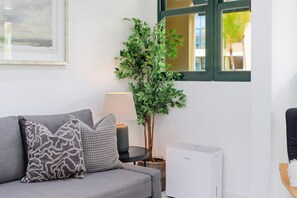 A grey sofa with patterned cushions, a potted plant, a lamp, and a white radiator. - AQUATIKA!!!5 Pools, Hot Tubs, Lazy River, Beach, Tennis, Mini golf, pickleball (Mediania Alta)