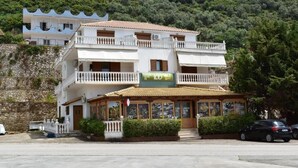 A two-story building with a restaurant on the ground floor, featuring a signboard and a balcony.
