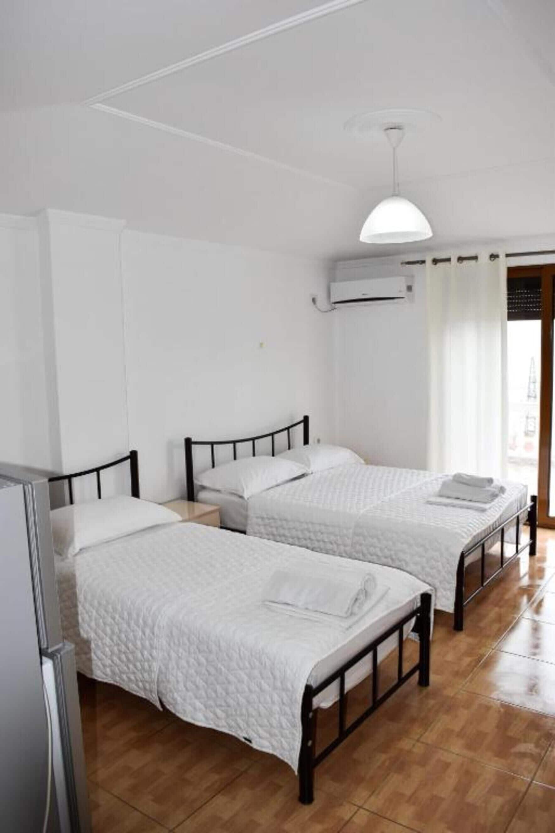 Una stanza con due letti, una ventola a soffitto e un condizionatore.