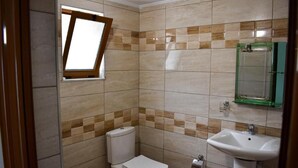 A small bathroom with a toilet, sink, and a window.