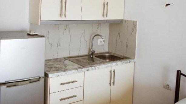 A compact kitchenette with a sink, cabinets, and a refrigerator.