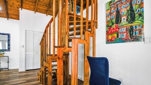 A wooden staircase with a blue chair in a room with white walls and a colorful painting. - Cute Farm 1 Cozy 2-bedroom cottage in lovely St. Cloud with AC (St. Cloud)
