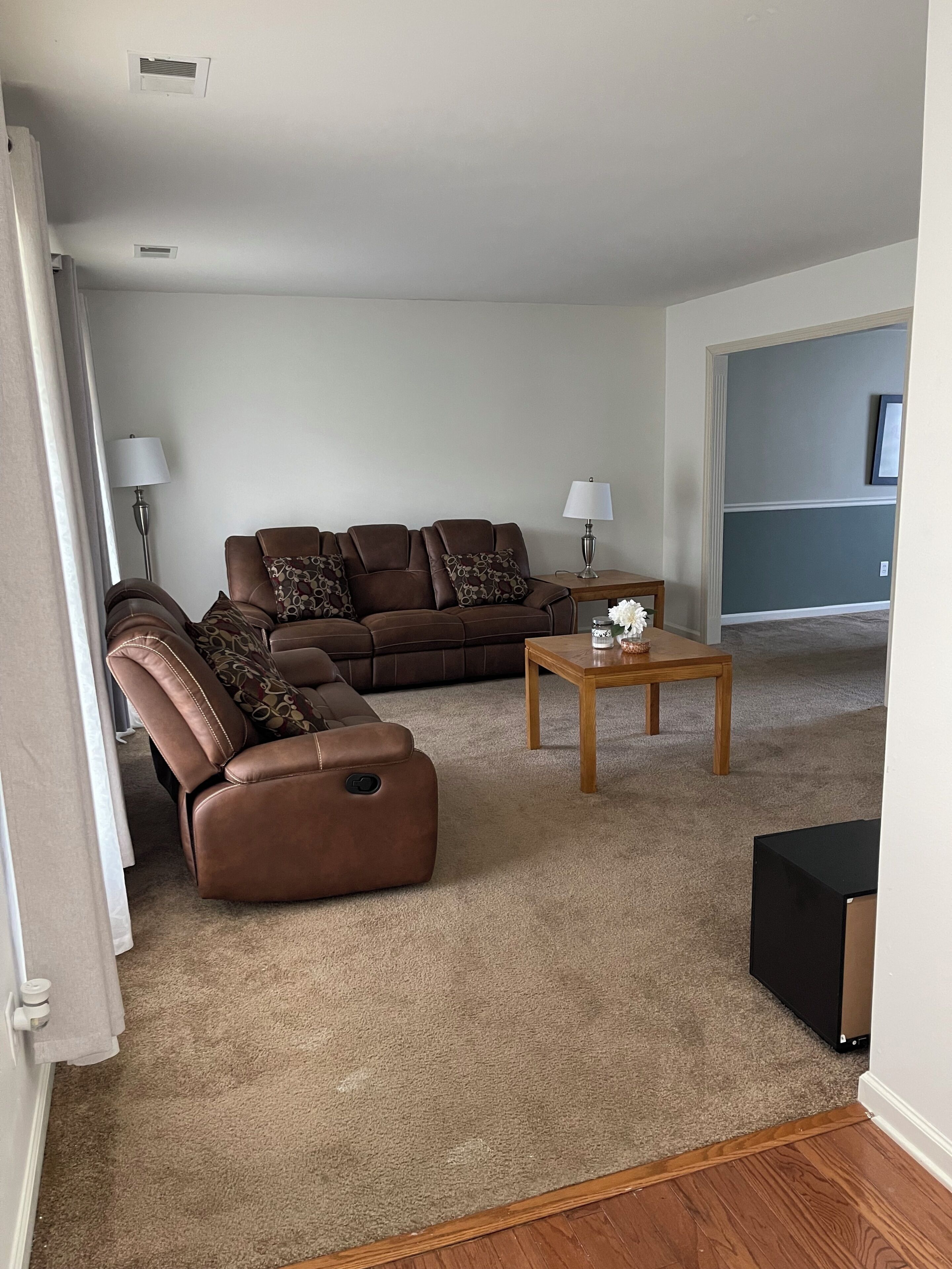 A living room with a brown leather sofa, a wooden coffee table, and a lamp.