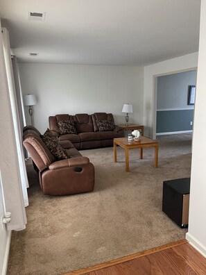 Ein Wohnzimmer mit einem braunen Ledersofa, einem Holztisch und einer Lampe.