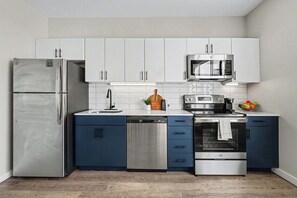 A modern kitchen with stainless steel appliances, white cabinets, and a blue countertop. - Sway - Pool - Gym - Mins to Broadway (Nashville)
