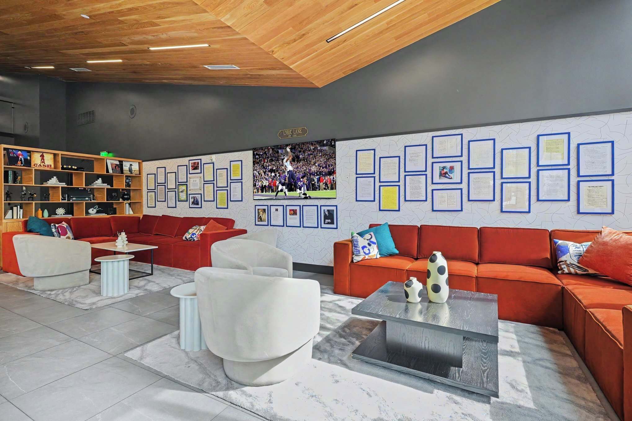 Un área de estar moderna con sofás, una mesa de centro y una pared decorada con diplomas enmarcados.