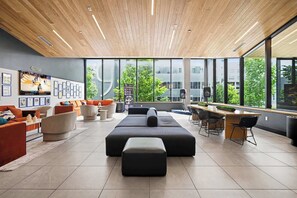 A modern lounge area with a wooden ceiling, large windows, and a seating arrangement including sofas and a bar. - Sway - Pool - Gym - Mins to Broadway (Nashville)
