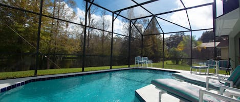 Una piscina techada con vistas despejadas a los árboles circundantes y un área con césped.