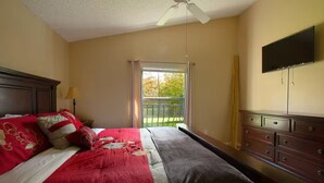 A hotel room with a bed, a dresser, a television mounted on the wall, and a window with curtains. - 3Bed/2Bath Lakeside Tranquility (Kissimmee)