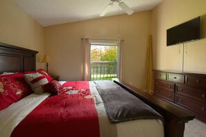 Ein Hotelzimmer mit einem Bett, einem Schminktisch, einem an der Wand befestigten Fernseher und einem Fenster mit Vorhängen.
