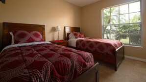 A bedroom with two beds, a ceiling fan, a window with blinds, and a nightstand with a lamp. - 3Bed/2Bath Lakeside Tranquility (Kissimmee)