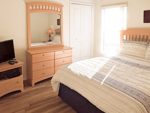 A bedroom with a bed, a dresser, a TV, and a mirror. - Newly Remodeled Home with a Private Pool and Hot Tub, Right Next to Disney! (Davenport)