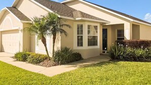 Ein eingeschossiges Haus mit Garage, Veranda und einer Palme.