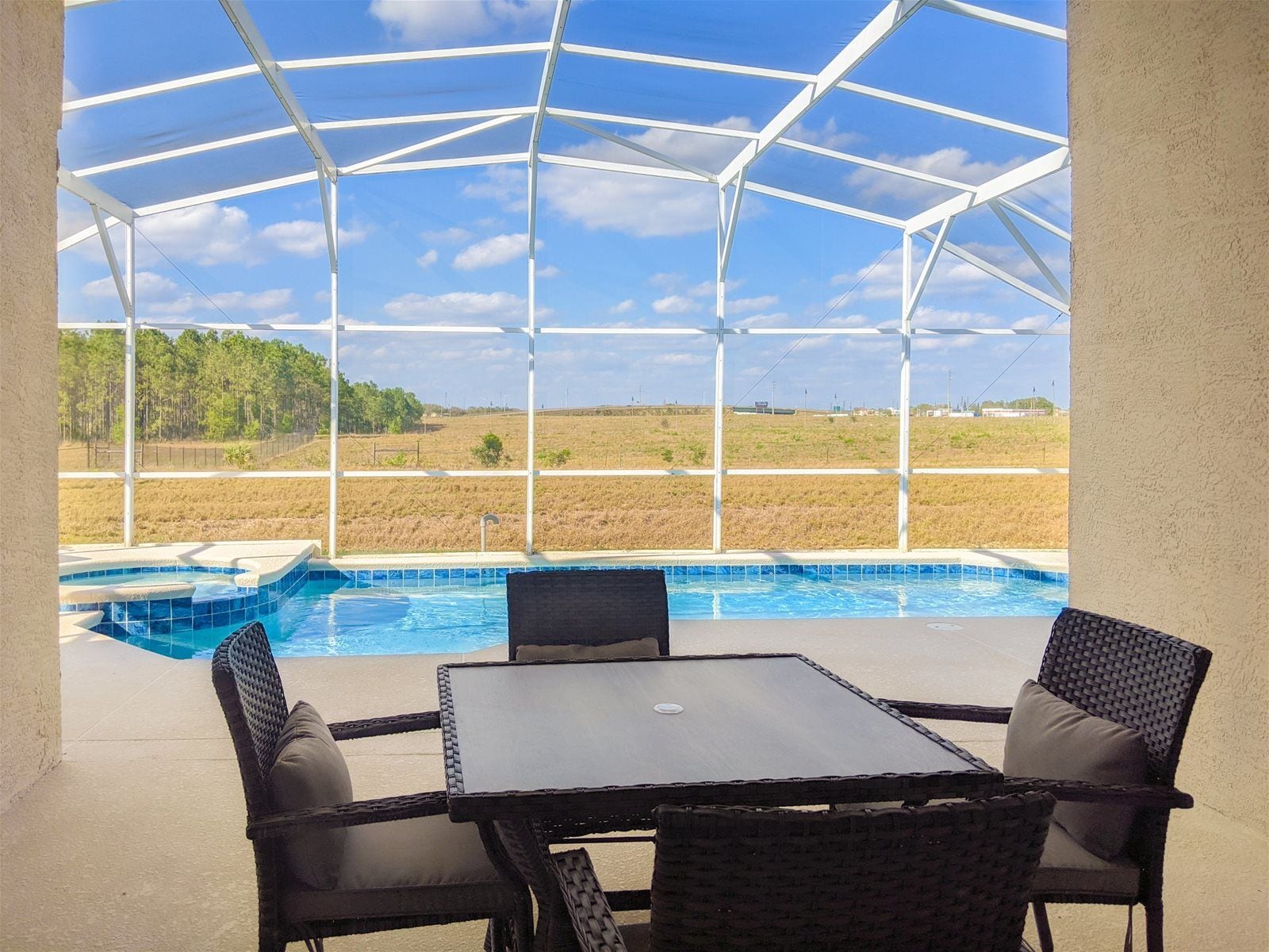 Un espacio al aire libre cubierto con piscina, dos sillones de mimbre y una mesa.