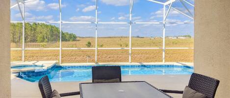 Un espacio al aire libre cubierto con piscina, dos sillones de mimbre y una mesa.
