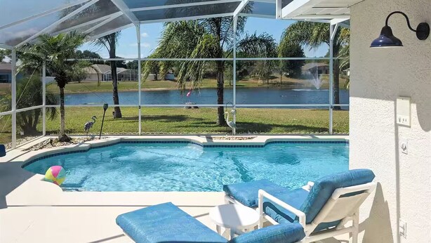 A pool area with a glass enclosure, lounge chairs, and a view of a natural landscape. - 4Bed/3Bath Sunny Lakeview Escape (Davenport)