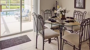 A dining area with a glass table and metal chairs, a small round table with candles, and a view of a swimming pool through large glass doors. - 4Bed/3Bath Sunny Lakeview Escape (Davenport)