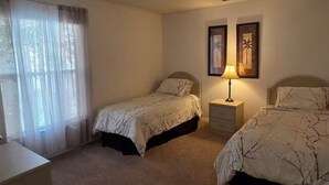 A bedroom with two beds, a nightstand, a lamp, and a window with sheer curtains. - 4Bed/3Bath Sunny Lakeview Escape (Davenport)