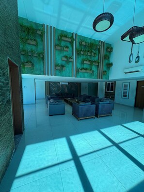 A modern interior with a high ceiling, a wall-mounted plant display, and a seating area with sofas and a coffee table. - Flamboyant Bessa Flat  (João Pessoa)