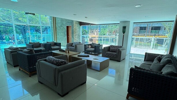 A spacious living room with a large window, a sofa set, and a coffee table. - Flamboyant Bessa Flat  (João Pessoa)