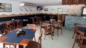 A restaurant with booths and tables, a television screen, and a mural on the ceiling. - Flamboyant Bessa Flat  (João Pessoa)