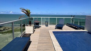 A pool area with lounge chairs and a view of the ocean. - Flamboyant Bessa Flat  (João Pessoa)