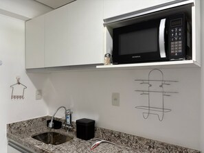 A kitchen with a built-in microwave, a stainless steel sink, and a marble countertop. - Flamboyant Bessa Flat  (João Pessoa)