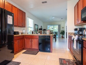 Fully stocked kitchen with granite countertops, stainless steel appliances, breakfast bar, and breakfast nook. - Luxurious 5 Bed/4 Bath with Private Pool and Nature Views Right Beside Disney! (Kissimmee)