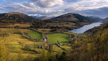 A mountainous landscape with a river, fields, and a lake.