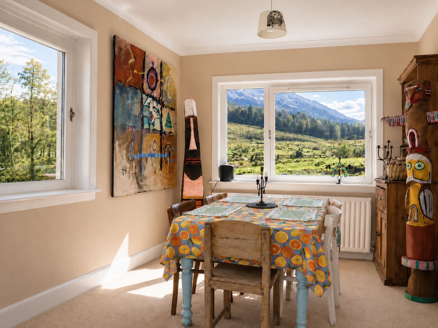 A dining area with a table set for four, a view of a mountainous landscape through large windows, and a rustic wooden cabinet with a carved figure.