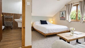 Quarto com cama, mesa de cabeceira e janela com cortinas.