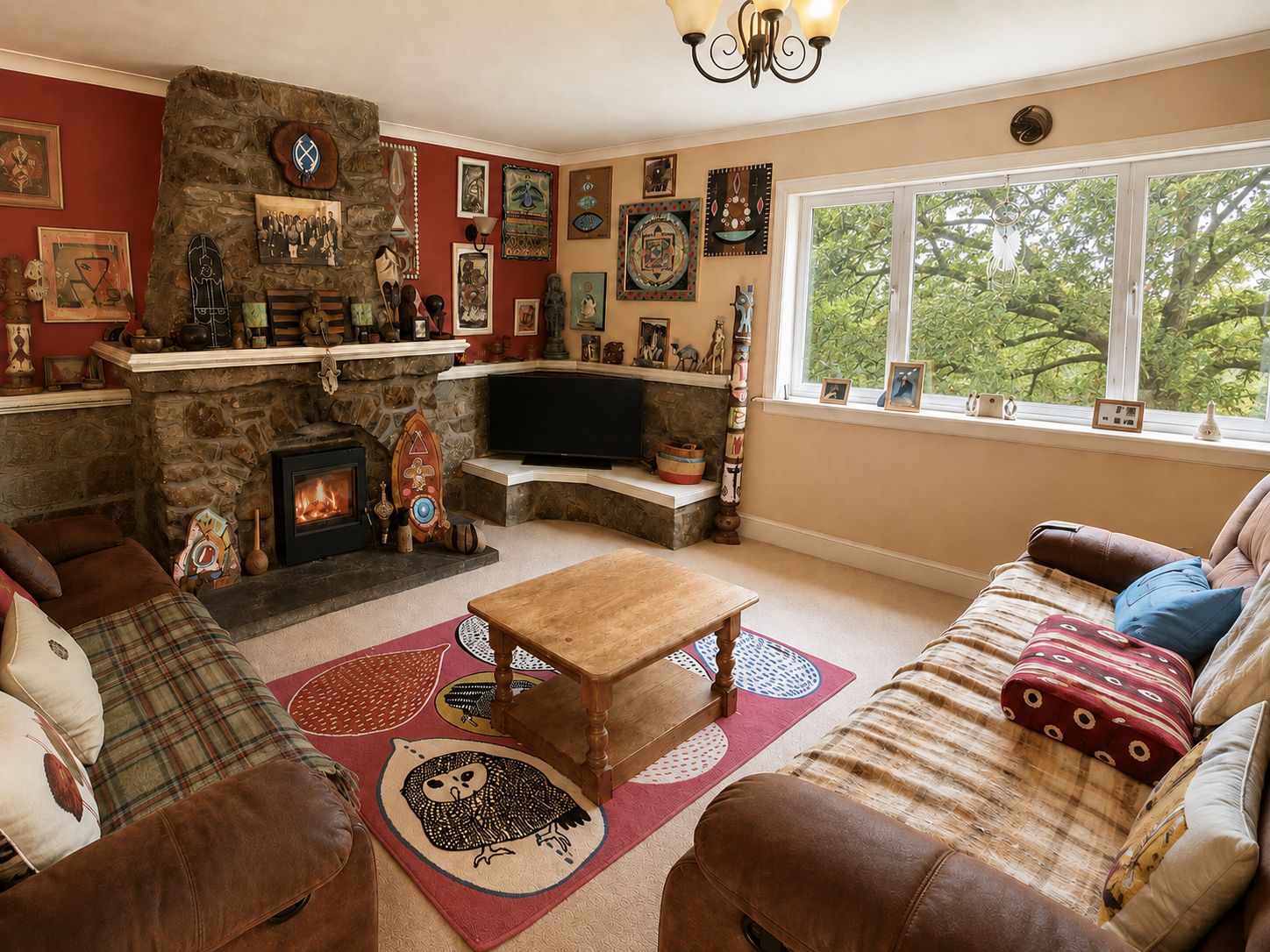A cozy living room with a stone fireplace, a television, and various wall art.