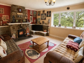 A cozy living room with a stone fireplace, a television, and various wall art. - CRAGMHOR (Balquhidder)