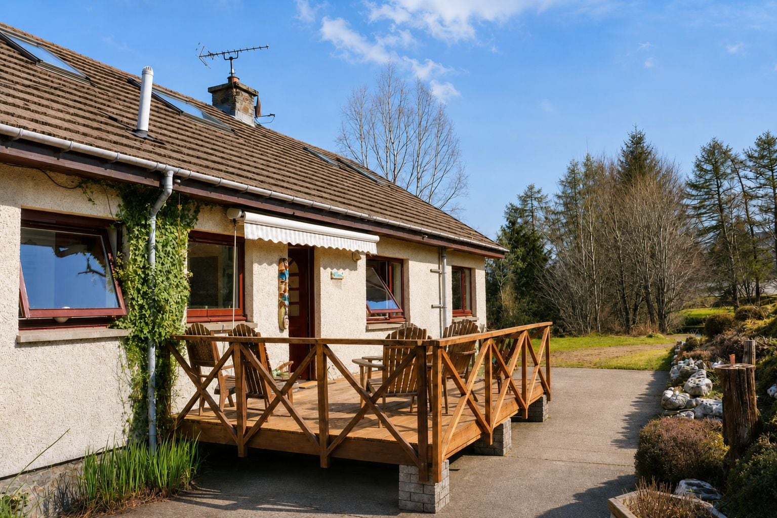 A house with a wooden deck, a chimney, and a window with a view of the sky.