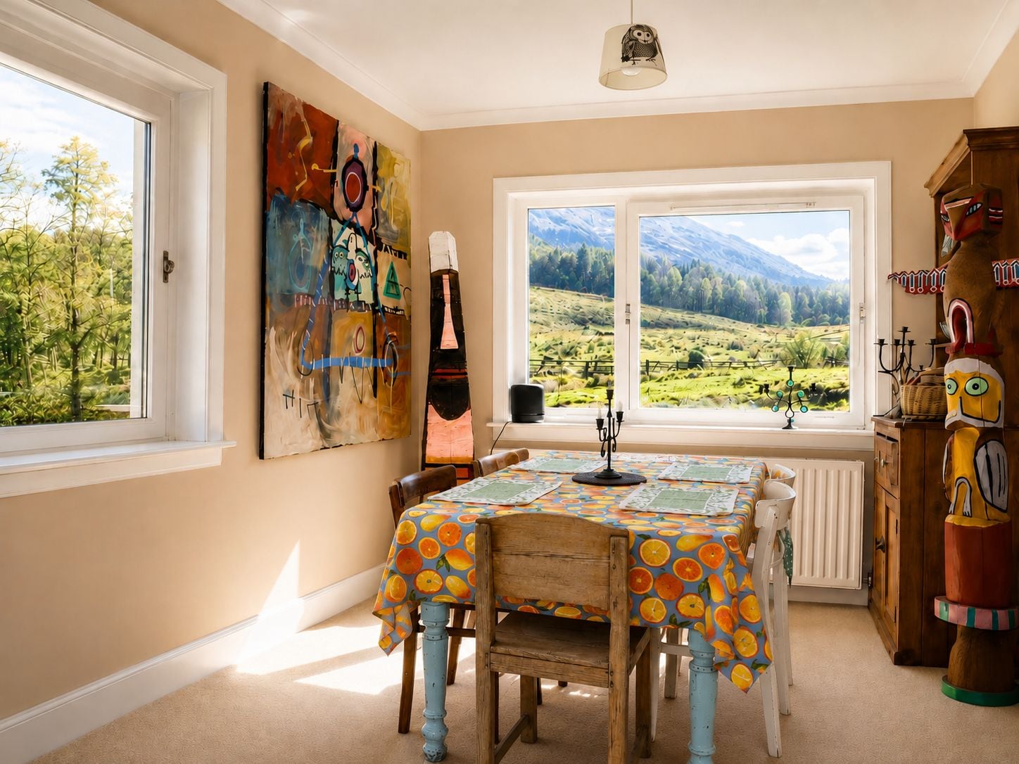 Ein Essbereich mit Tisch für vier Personen, Blick auf eine gebirgige Landschaft durch große Fenster und eine rustikale Holzkabine mit Dekoration.