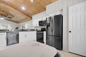A modern kitchen with white cabinetry, stainless steel appliances, and a wooden ceiling. - Chatham Park Private Pool Retreat (Kissimmee)