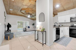 Ein geräumiger Wohnbereich mit hoher Decke, eine Küche mit modernen Geräten und ein Essbereich mit Tisch und Stühlen.
