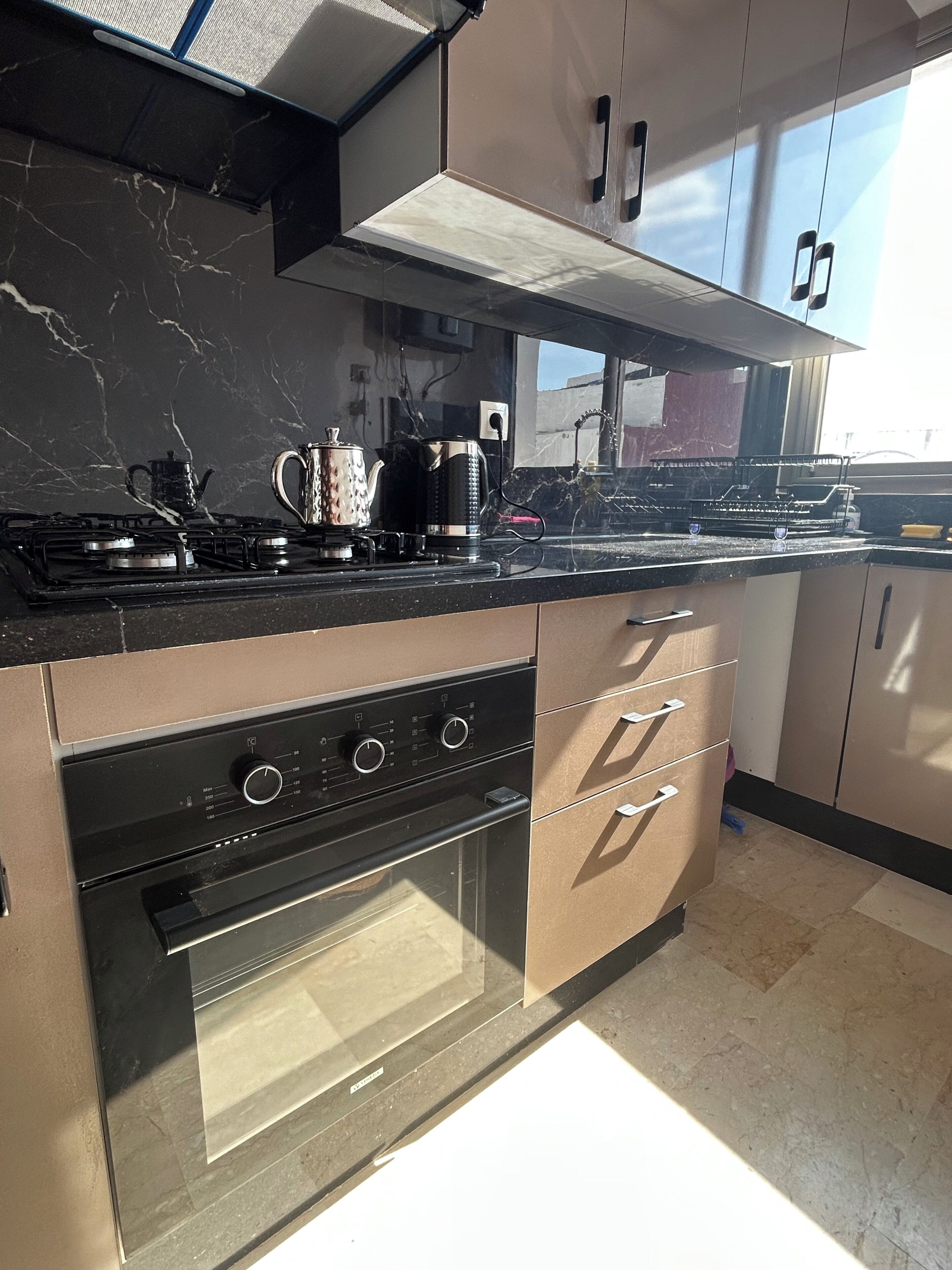 Een moderne keuken met een gasfornuis, oven en roestvrijstalen apparatuur.