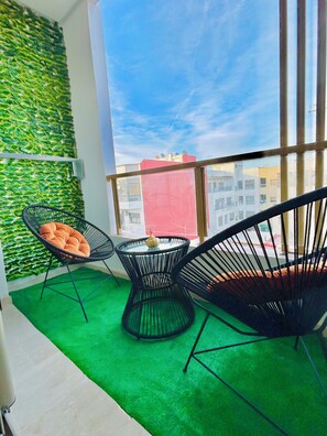 A balcony with two black wire-framed chairs, a small round table, and a green artificial grass floor. - Luxury Stay (Casablanca)