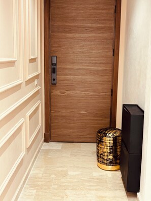 A hallway with a wooden door, a textured ottoman, and a black speaker. - Luxury Stay (Casablanca)