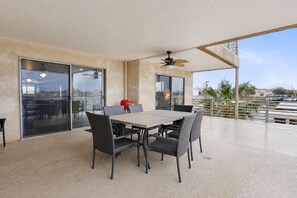 An outdoor patio with a table and chairs, a ceiling fan, and a view of the cityscape.