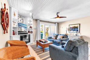Ein Wohnzimmer mit Fernseher, Bücherregalen, Couchtisch und Sofa.
