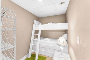 A bunk bed with a ladder, a small bedside table with a lamp, and a green rug on the floor. - Ocean Mile A-2, Pool Front with Unobstructed Beach View, Boardwalk (St. George Island)