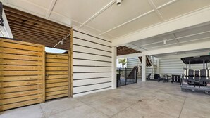 Un espacio descubierto y cubierto con un portón de madera, una zona de estar con mesas y sillas, y vistas a una escalera que conduce a un nivel superior.