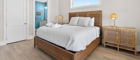 Un dormitorio con cama de madera, mesita de noche con lámpara, ventilador de techo y ventana con vistas.
