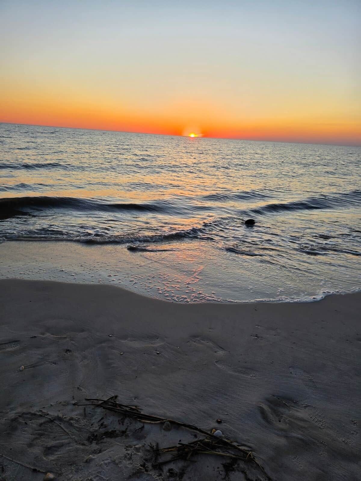 A beach with waves and a sunset.