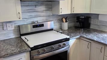 A kitchen with white cabinets, a stainless steel range hood, a built-in oven, and a granite countertop.