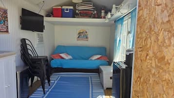 A compact room with a blue sofa, a small table, and a television mounted on the wall.