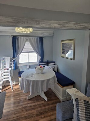 Een kamer met een ronde tafel, een bank en een raam met gordijnen.