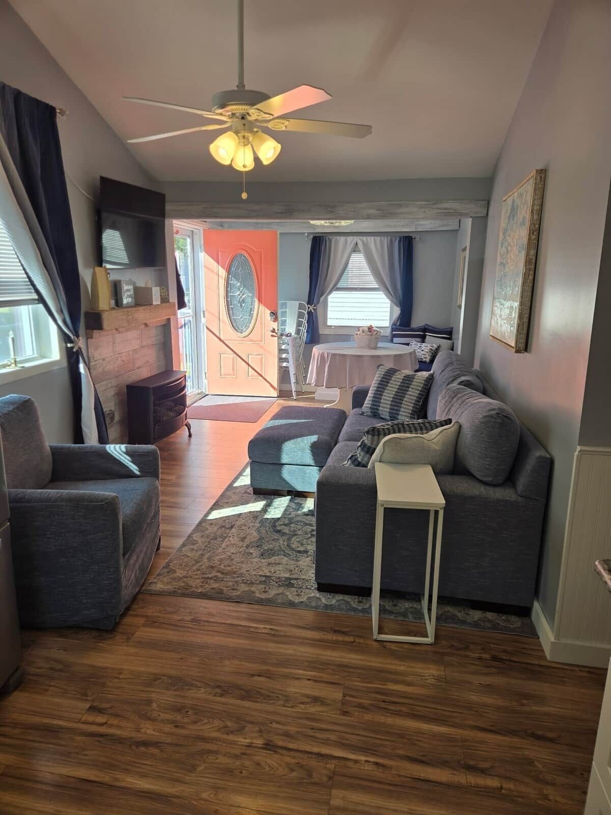 A living room with a sofa, a coffee table, and a ceiling fan. There is a door leading to another room.